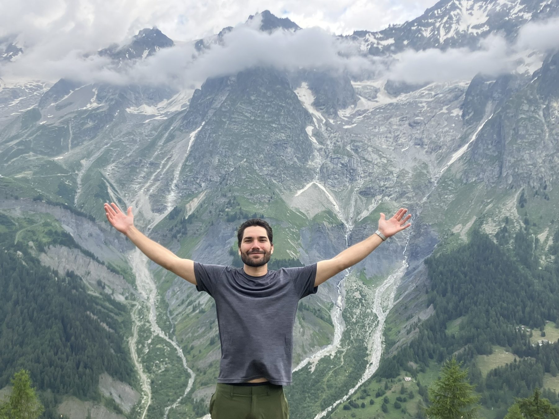 Ben Gutierrez with his arms out in front of a mountain range